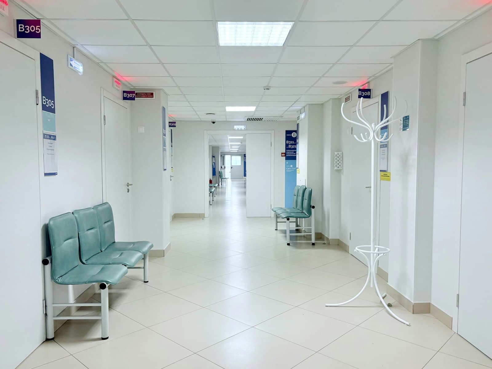 Heller Klinikflur mit Sitzbänken und Behandlungszimmertüren